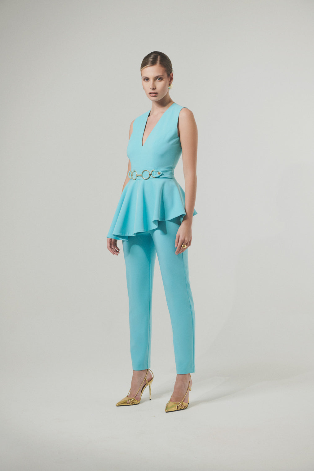 Elegant jumpsuit in technical fabric with ruffles and metallic decoration at the waist